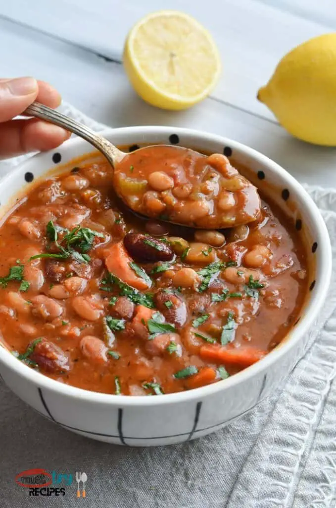 Instant Pot 15 Bean Soup Vegetarian in a white bowl, the soup being lifted with a spoon