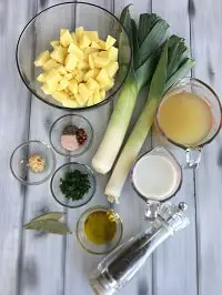 diced potatoes in a clear bowl along with other ingredients on a grey board