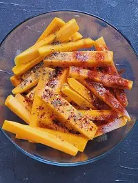butternut squash fries with seasonings in a clear bowl