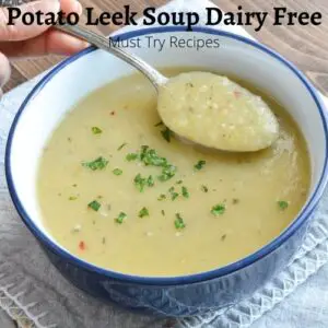 vegan potato leek soup in a blue bowl garnished with parsley & soup being lifted with a spoon