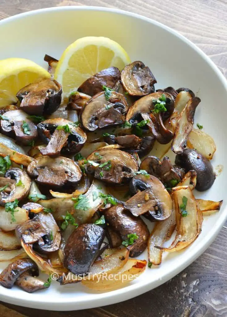air fryer mushrooms and onions served with lemon wedges on a white plate