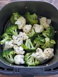 seasoned broccoli and cauliflower florets in air fryer basket