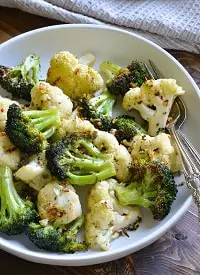 air fryer broccoli and cauliflower served on a white plate with fork and spoon