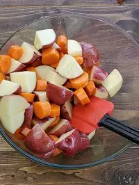 tossing carrots and potatoes in a bowl with oil