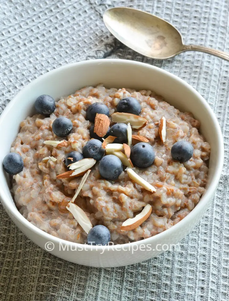 instant pot buckwheat porridge garnished with fresh blueberries & silvered almonds in a white bowl