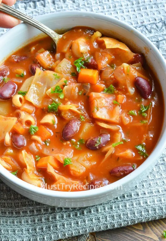 instant pot Portuguese bean soup in a white bowl with a spoon