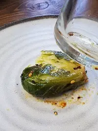 smashing one brussel sprout with a clear drinking glass