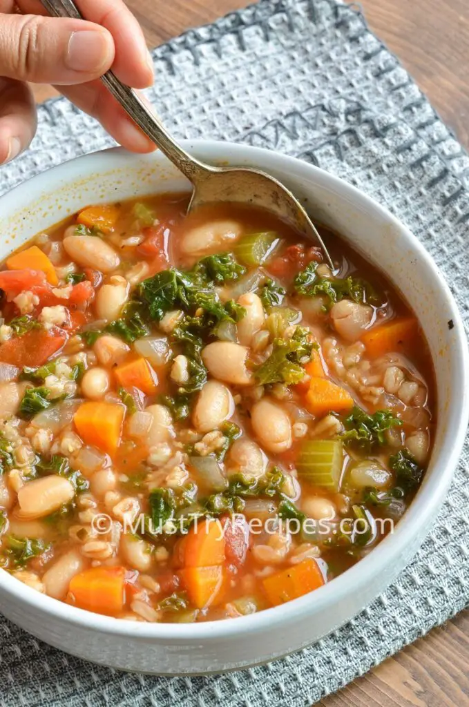 instant pot farro soup in a white bowl with a spoon