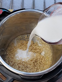 pouring coconut milk on top of rinsed brown rice in instant pot