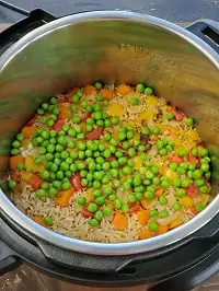 pressure cooked brown rice and vegetables, green peas spread on top