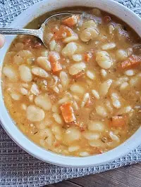 lima beans soup in a white bowl with a spoon