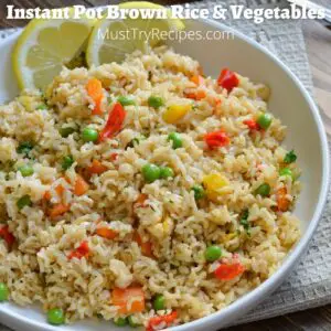 brown rice and vegetable on a white plate with lemon slices