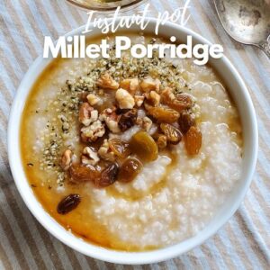 Millet porridge in a white bowl topped with walnuts, hemp seeds & maple syrup.