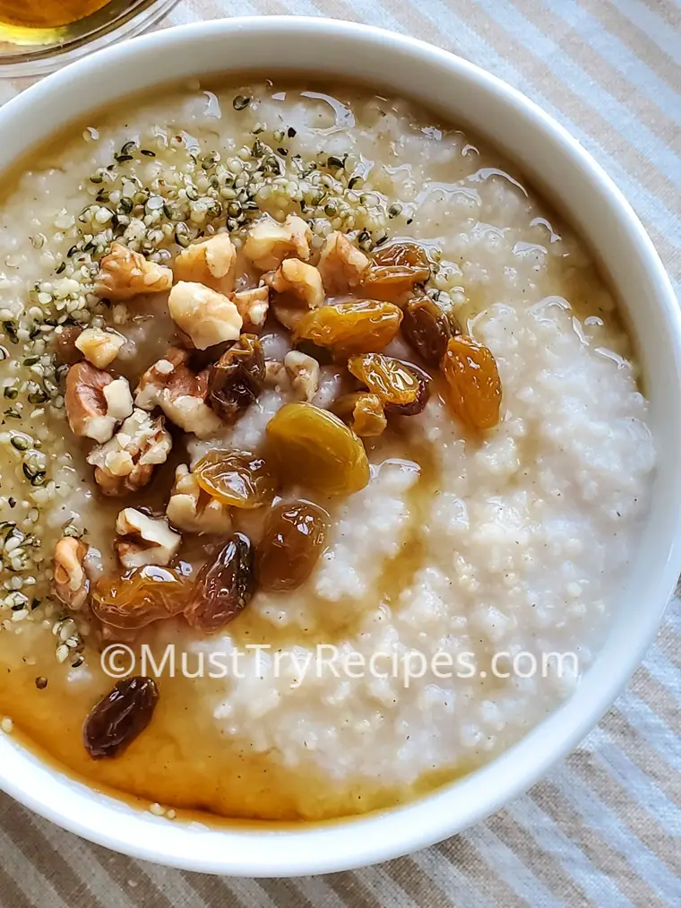 vegan millet porridge garnished with walnuts, hemp seeds, raisins, and maple syrup.