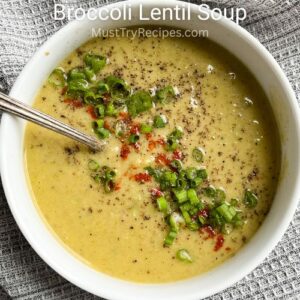 broccoli lentil soup in a white bowl with a spoon and garnished on top