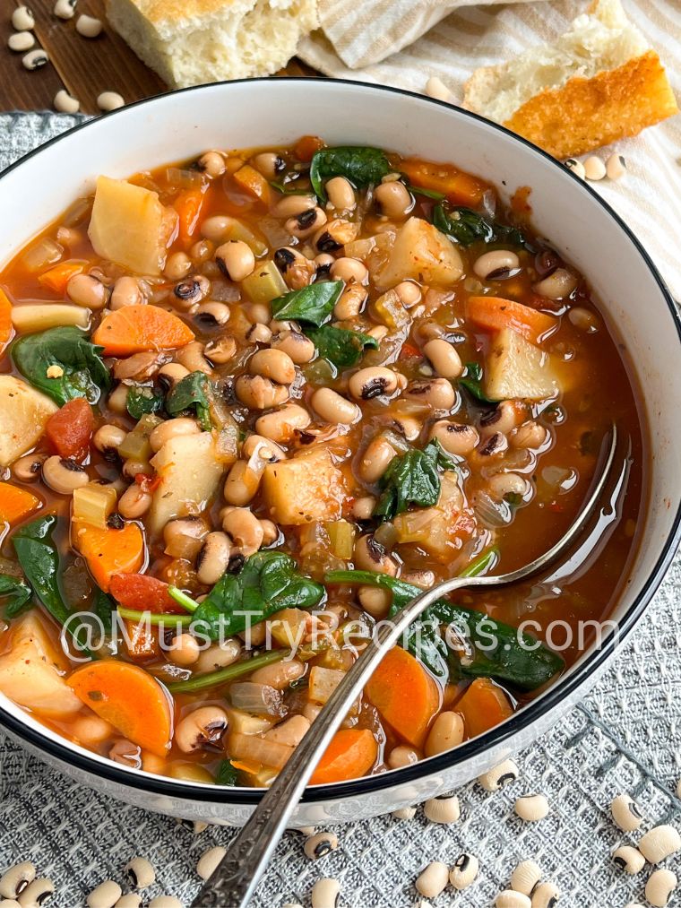simple black eyed peas soup recipe served in a black rimmed white bowl with a silver spoon.
