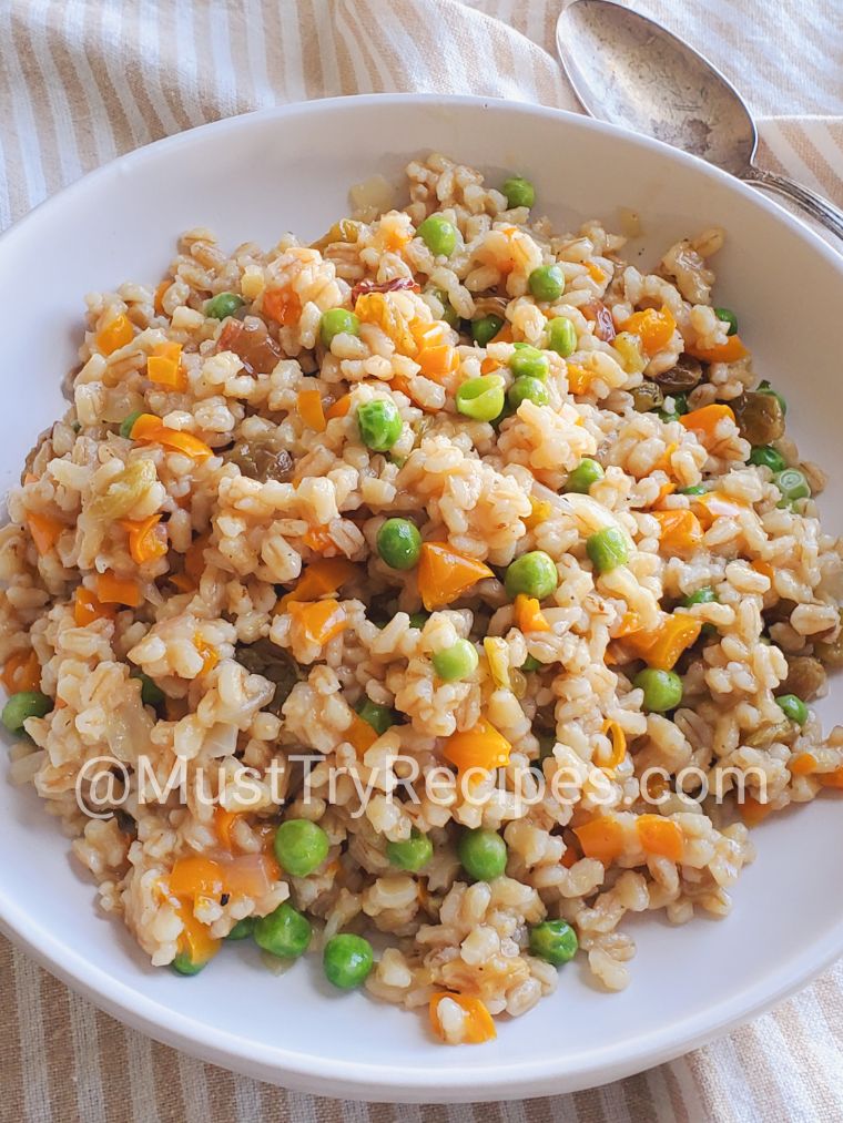 Simple barley pilaf recipe with vegetables served in a white plate