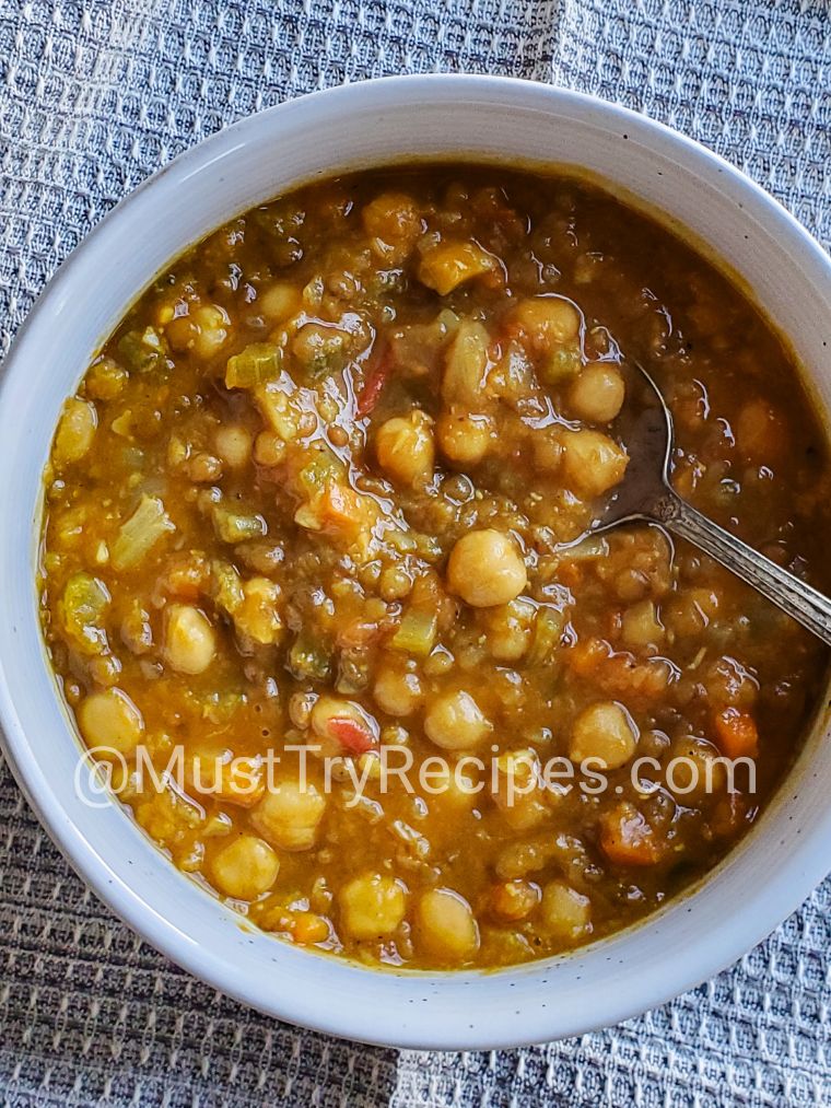 Moroccan chickpea soup served in a white bowl with a silver spoon.