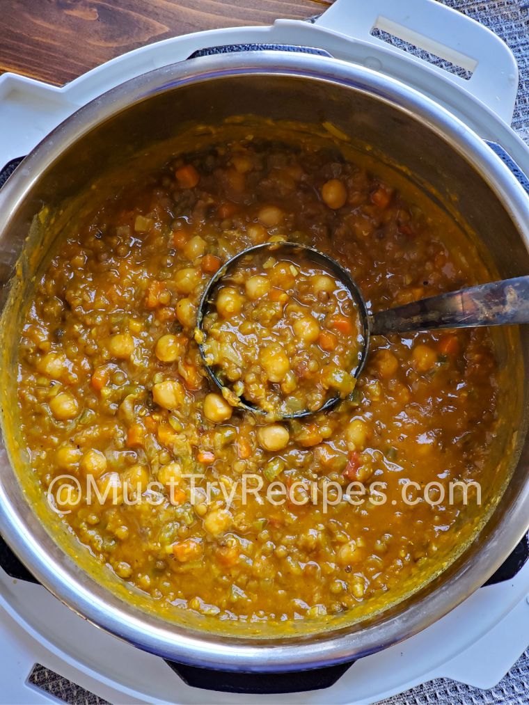 Moroccan soup with chickpeas in a white instant pot with a silver ladle.